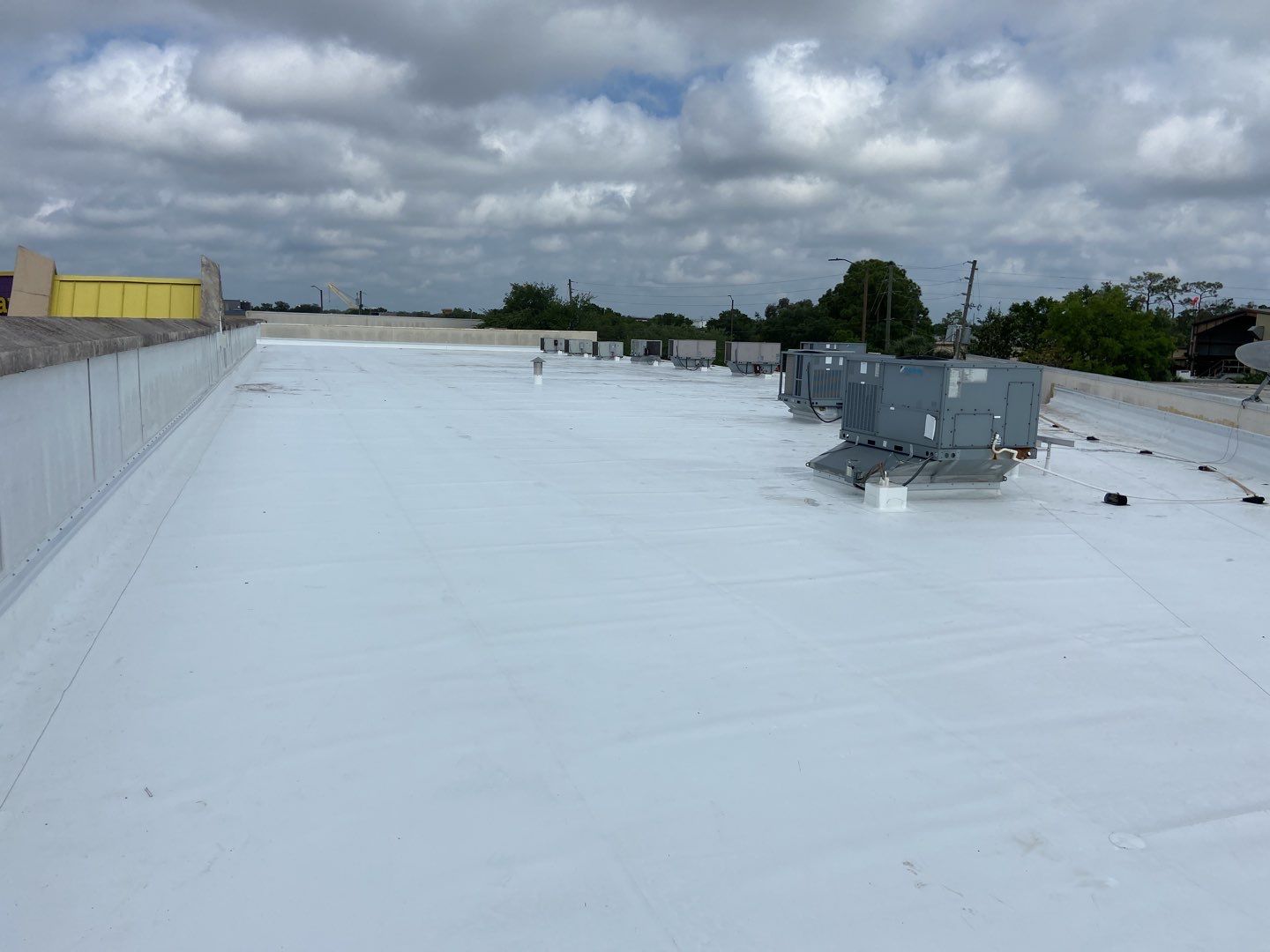 White TPO single-ply flat roof with rooftop HVAC units on a commercial building