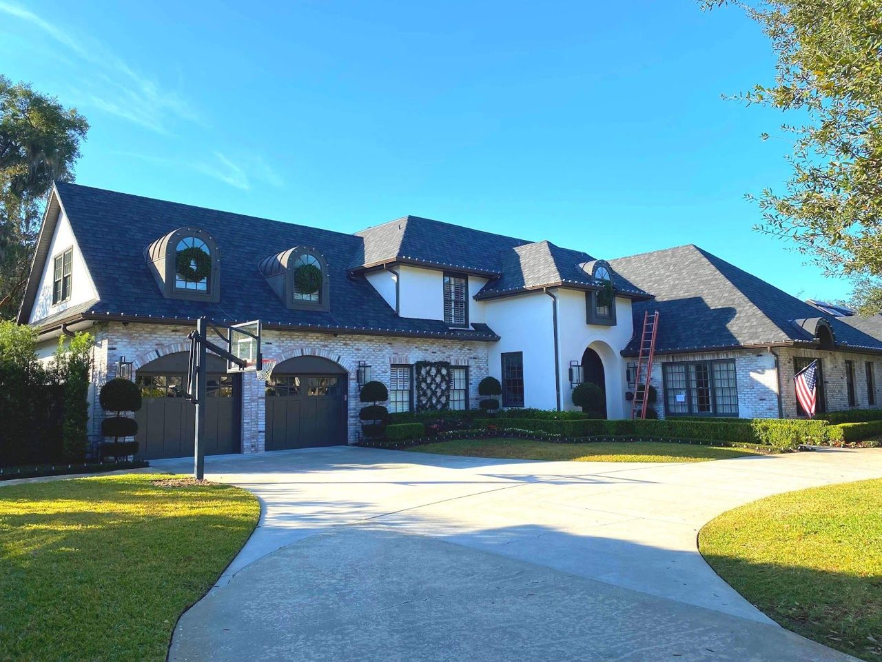 Dark architectural shingle roof with dormers on a two-story brick and stucco home
